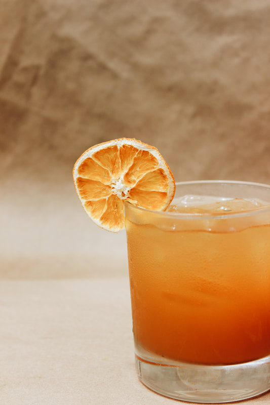 A bourbon cocktail with a dried orange garnish