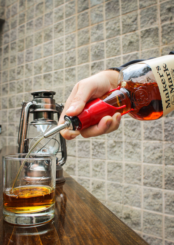 A bartender pouring a bottle of Maker's Mark Whisky